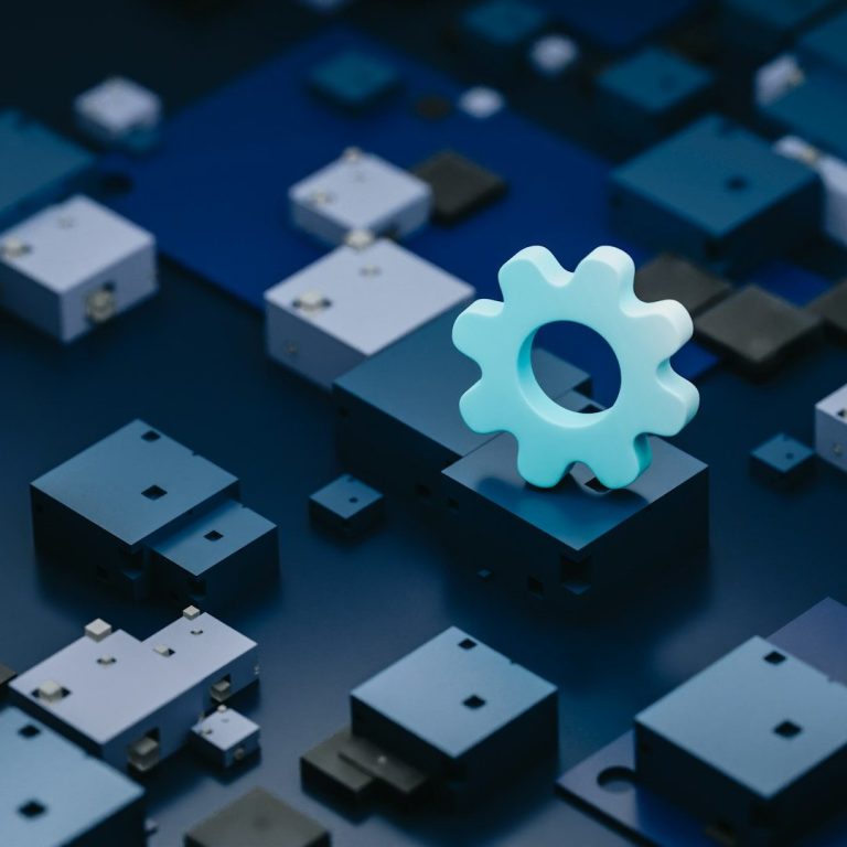 Abstraktes Bild: blaue Quader auf einer glatten blauen Oberfläche, auf einem Quader steht eine Form, die an ein Zahnrad erinnert